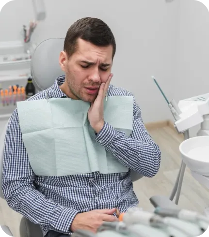Homem com a mão no rosto sentindo dor de dente na cadeira do dentista